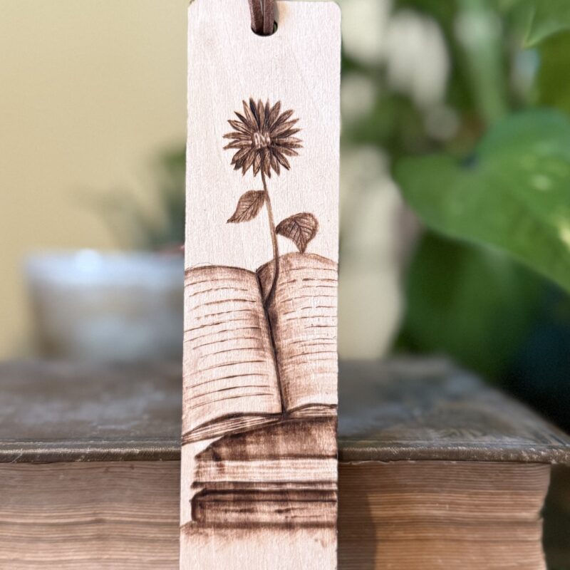 wooden bookmark with an image of a flower growing out of a book